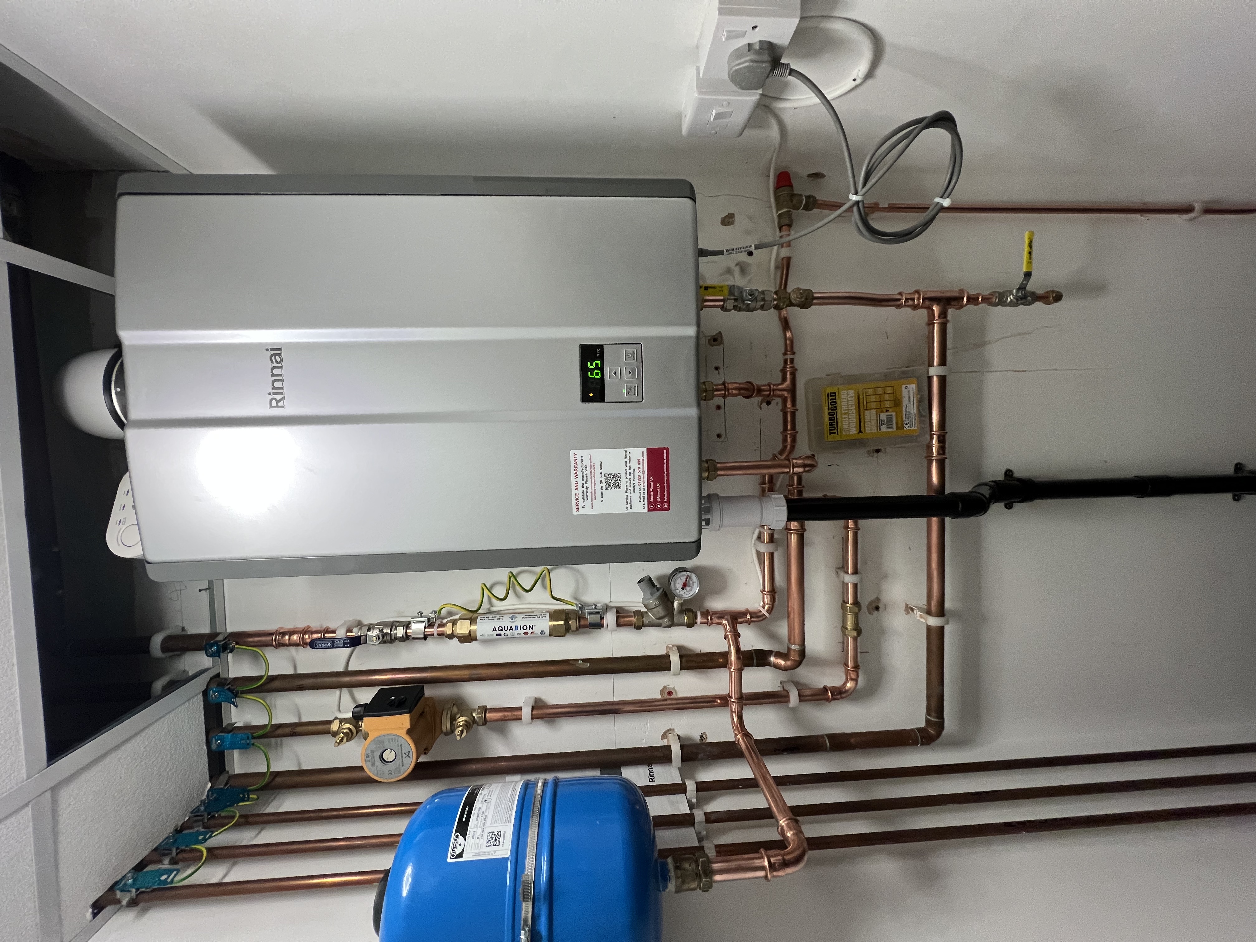 Wall-mounted Rinnai unit with copper pipework and expansion vessel