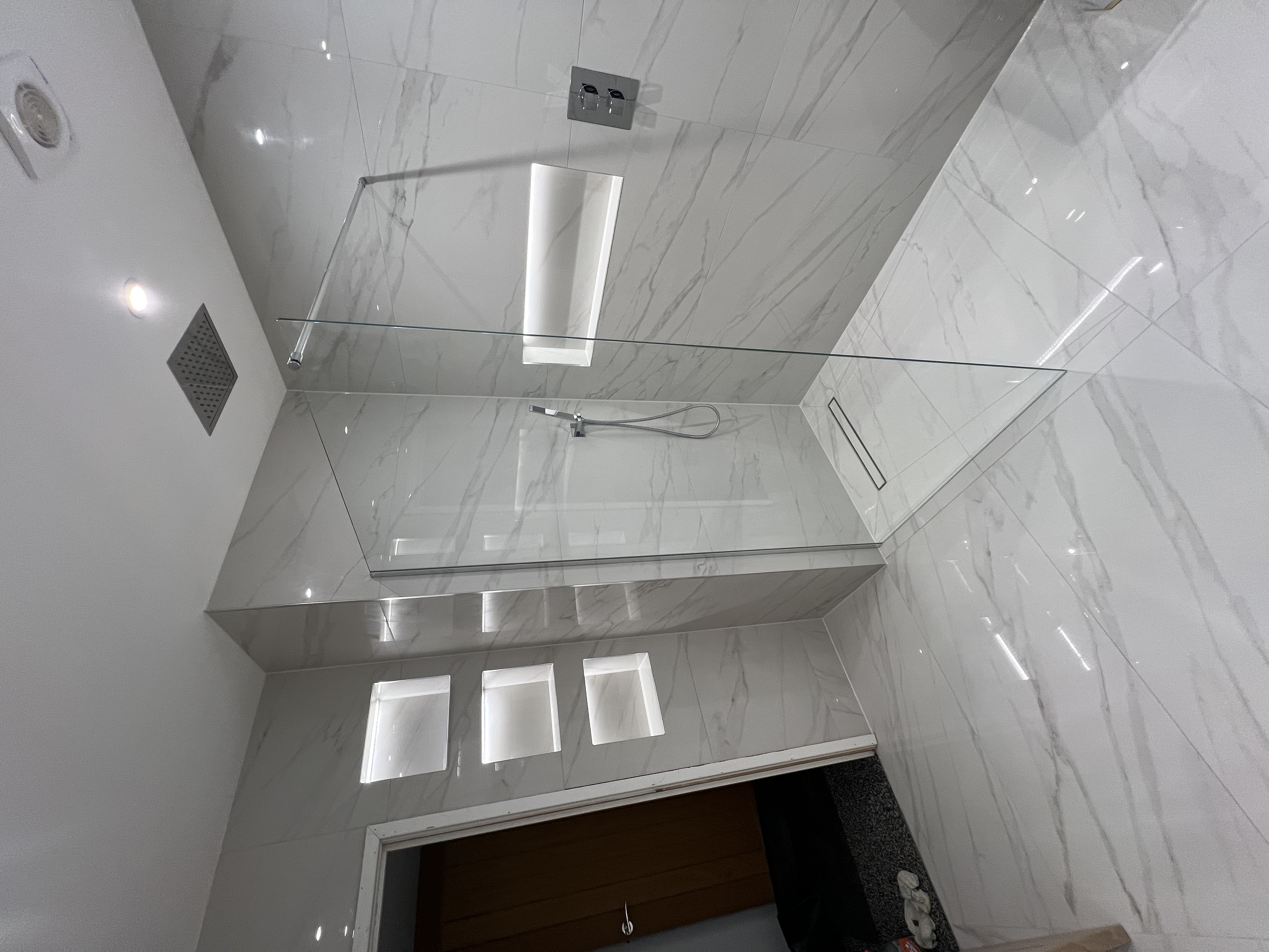 Walk-in shower with marble-effect tiles and recessed shelves